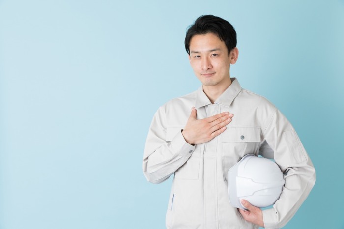 胸に手を当てる男性・作業着